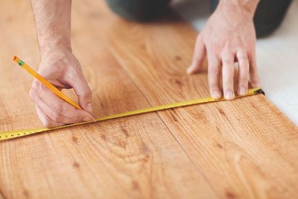 Person vermisst Holzboden mit Zollstock.